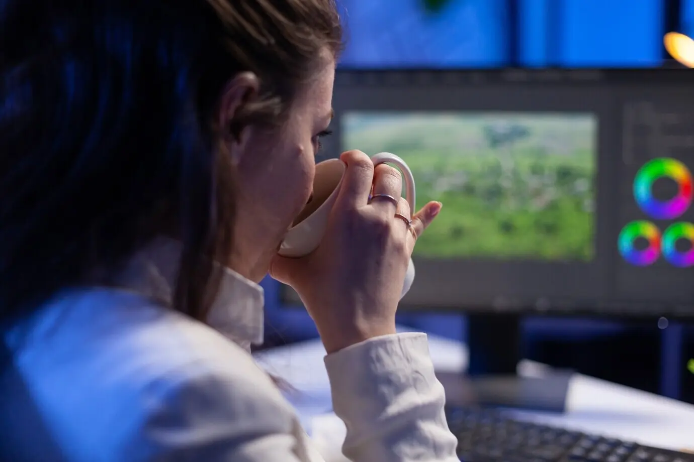 Сосредоточенный редактор-ретушёр выполняет цветокоррекцию на профессиональном компьютере.